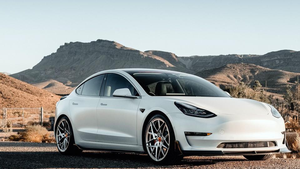 ein weißer Tesla auf einer Schotterstraße in freiem, hügeligem Gelände