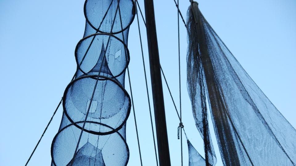 feinmaschige Fischernetze, die vertikal an einem Mast zum Trocknen aufgehängt wurden